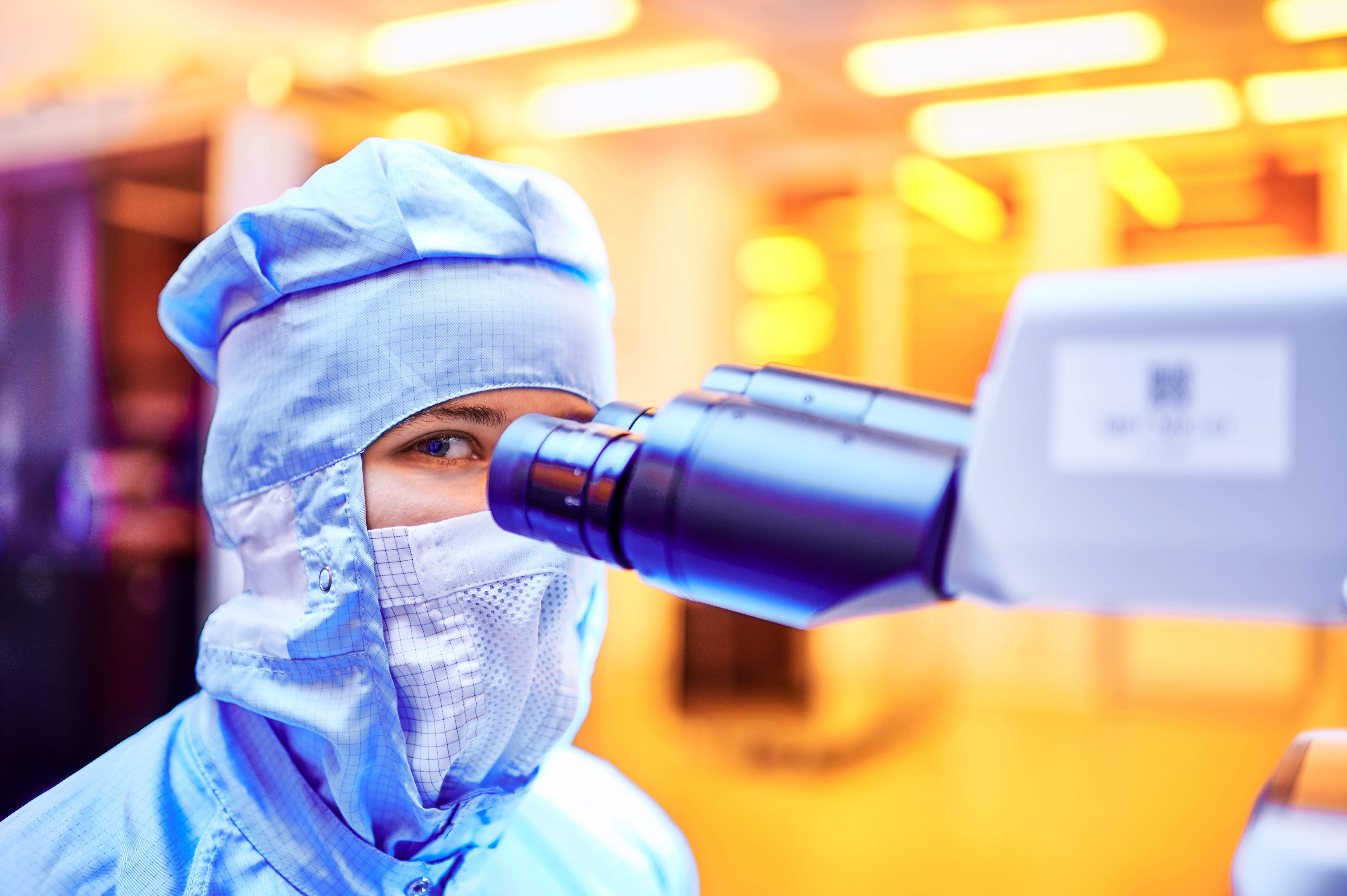 Ein Auszubildender der Mikrotechnologie arbeitet mit einem Mikroskop.
